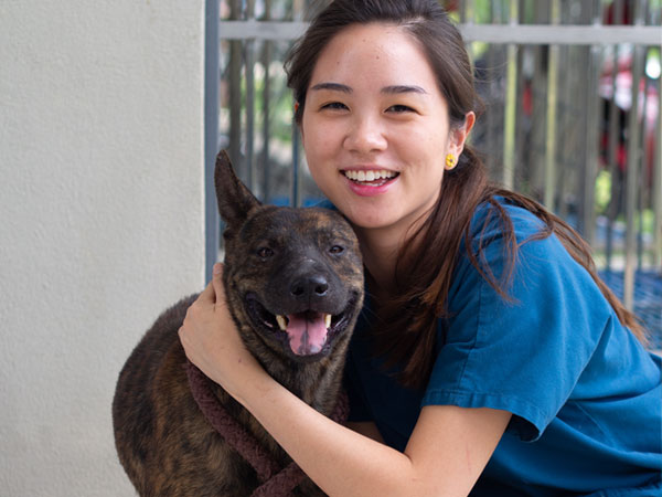 A smiling girl posing with a black dog